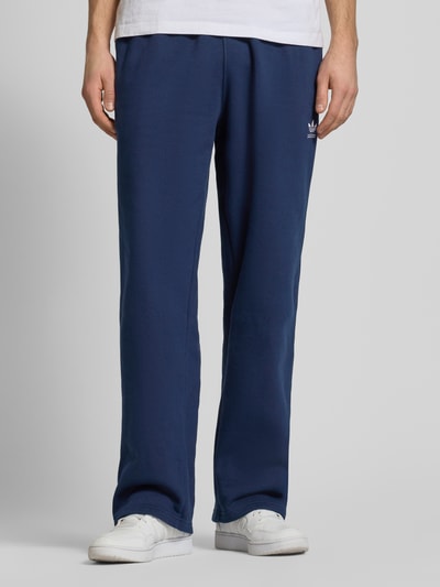 Männermodel trägt Wide Fit Sweatpants mit elastischem Bund von adidas Originals in Dunkelblau, Baumwoll-Mix, Nahaufnahme Unterkörper.
