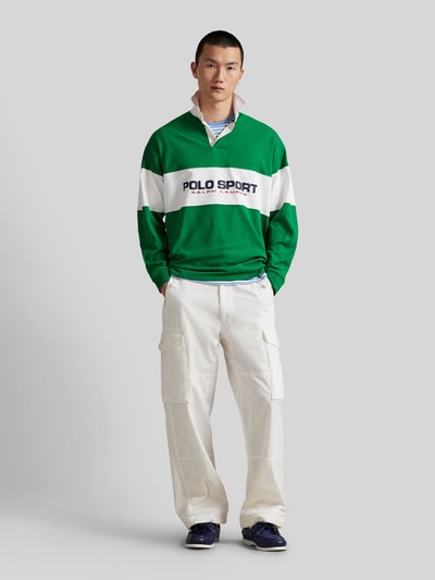 Männermodel trägt Regular Fit Poloshirt aus reiner Baumwolle von Polo Ralph Lauren, grün-weiß, langarm, Piqué-Struktur, Ganzkörperansicht von vorne.