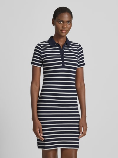 Vrouwenmodel draagt Knielanges Polokleid mit kurzer Knopfleiste van Gant, navy-wit gestreept, aansluitende fit, katoenmix met stretch, polokraag, korte knoopsluiting, knielang, vooraanzicht bovenlichaam.