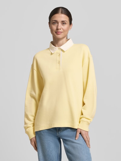 Frauenmodel trägt Longsleeve mit Polokragen und kurzer Knopfleiste von Gant aus Baumwoll-Mix, Loose-Fit, gerippte Ärmelabschlüsse, Ganzkörperansicht von vorne.
