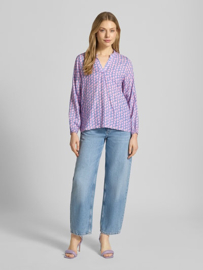 Frauenmodel trägt Bluse aus Viskose mit Serafino-Ausschnitt Modell 'Ja44nina' von ZABAIONE in Lila mit Allover-Muster, Lockerer-Schnitt, Elastische Ärmelabschlüsse, Rückenlänge 65 cm, Ärmellänge 56 cm, Ganzkörperansicht von vorne.