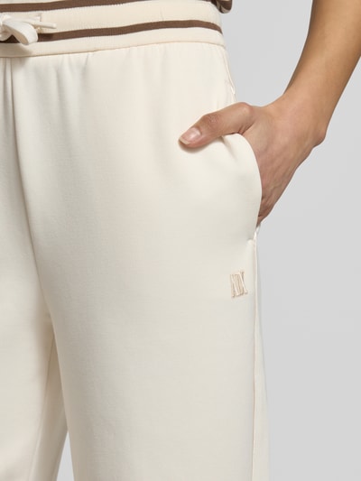 Kobiece modelka nosi spodnie dresowe z elastycznym pasem od ARMANI EXCHANGE, mieszanka wiskozy i elastanu, krój relaxed fit, paski w kontrastowym kolorze, długość wewnętrzna nogawki w rozmiarze S: 77 cm, detailaufnahme okolicy bioder