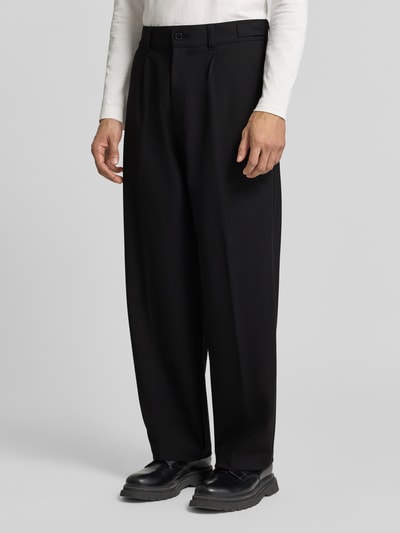 Mężczyzna nosi High Waist Bundfaltenhose mit Bügelfalten od HUGO, kolor czarny, szerokie nogawki, unikalna tekstura, Ganzkörperansicht von vorne.