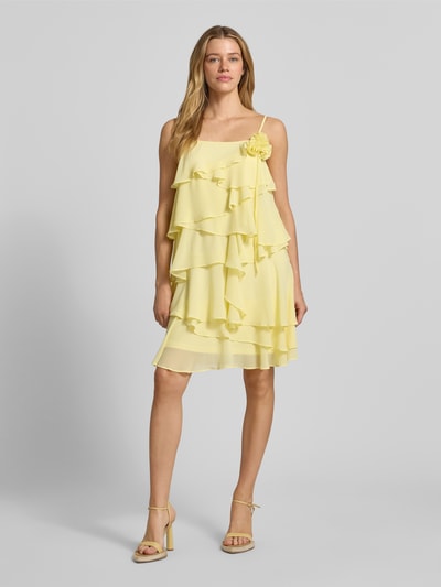 Vrouwenmodel draagt fließendes Cocktailkleid mit Volants Modell 'ALADYN' van Vero Moda, uni, fließende fit, mini-lengte, rechte hals, sierbloem, volants, verstelbare spaghettibandjes, geheel van voren.