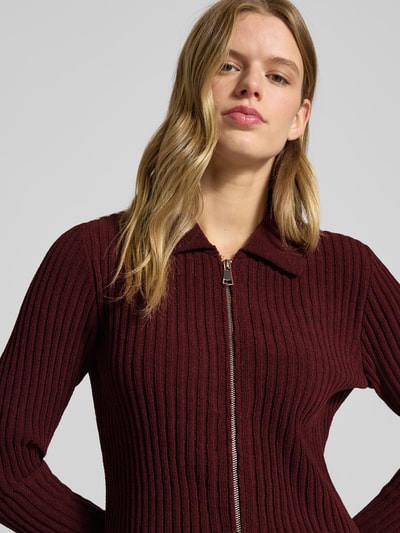 Kobiece model prezentuje Kardigan rozpinany Model 'ELLY' od Only, efekt: jednolity kolor z fakturą, krój regular fit, wykładany kołnierz, dekolt w serek, długi rękaw, wykończenie: prążkowana dzianina; zbliżenie na górną część sylwetki.