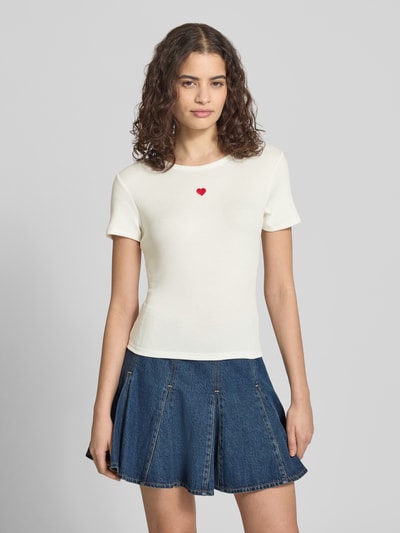 Frauenmodel trägt Slim Fit T-Shirt mit Herz-Stickerei Modell 'ELVA JUNE' von Only, einfarbig, aus Ripp, Ganzkörperansicht von vorne.