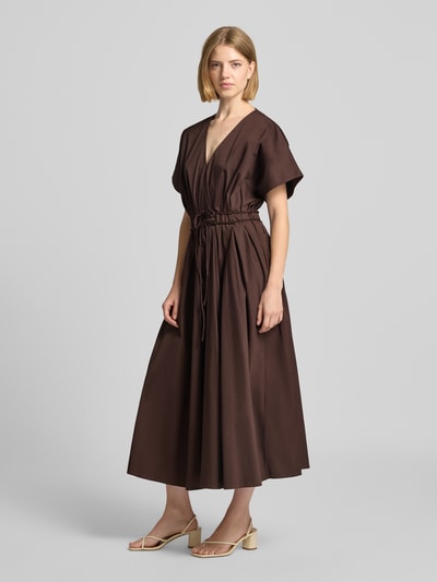 Frauenmodel trägt Cocktailkleid mit V-Ausschnitt und Schnürung von Christian Berg Cocktail, braun, A-Linie, Midikleid, Ganzkörperansicht von vorne.