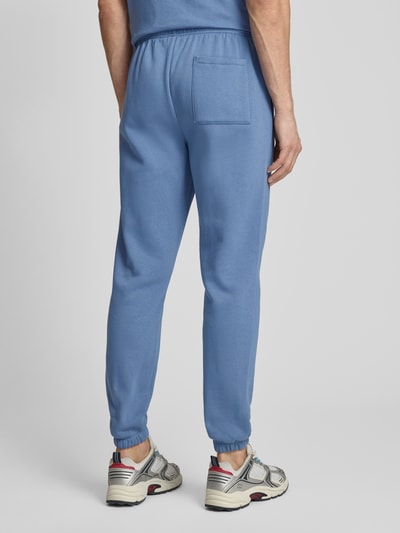 Männermodel trägt Sweatpants mit elastischem Bund von GAP aus Baumwoll-Mix, Regular-Fit, Gesäßtasche, Farbe Hellblau, Ganzkörperansicht Rückansicht. Innenbeinlänge bei Größe M: 74 cm.