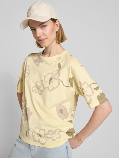 Modelka kobieta nosi T-Shirt im Allover-Look mit Rundhalsausschnitt von JAKE*S STUDIO WOMAN w jasnożółtym kolorze z kwiatowym wzorem, czysta bawełna, krój regular fit, długość tyłu w rozmiarze S: 57 cm, widok całej sylwetki z przodu.