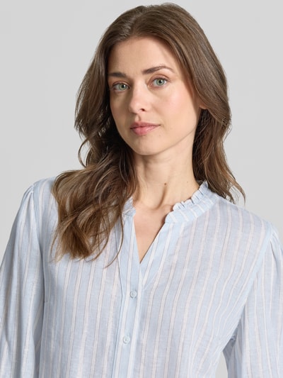 Frauenmodel trägt Regular Fit Hemdbluse aus Leinen-Viskose-Mix Modell 'VIOLET' von Brax, Optik: Allover-Muster, gestreift, mit Label-Applikation, Kragenform: Tunika, V-Ausschnitt, einreihige Knopfleiste, 3/4-Arm, Materialverarbeitung: Flammgarn, Nahaufnahme Oberkörper.