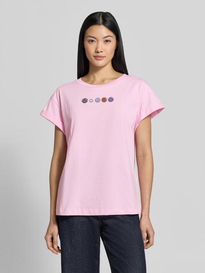 Frauenmodel trägt Relaxed Fit T-Shirt aus reiner Baumwolle von Rich & Royal, rosa mit Ziersteinen und fixierten Ärmelumschlägen, Ganzkörperansicht von vorne.