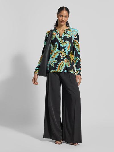 Vrouwenmodel draagt Regular Fit Bluse aus Seide-Elasthan-Mix van HERZENS, all-over print, tuniekkraag, zwart, blauw en geel, geheellichaamsaanzicht voorkant.