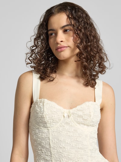 Frauenmodel trägt Slim Fit Top mit Allover-Spitzenbesatz von Gina Tricot, cremefarben mit Zierschleife und Spaghettiträger, Nahaufnahme Oberkörper. Damen Top, Rückenlänge bei Größe S: 24 cm.
