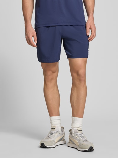 Männermodel trägt Shorts mit Logo und elastischem Bund von PUMA PERFORMANCE in Dunkelblau, reguläre Passform, Ganzkörperansicht von vorne.