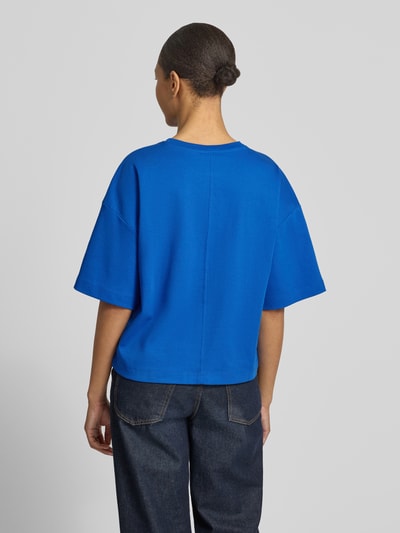 Frauenmodel trägt Oversized T-Shirt aus reiner Baumwolle von s.Oliver RED LABEL in Optik: Unifarben, Passform: Oversized, Logo-Applikation, Rundhals, Ärmelform: Kurzarm, Materialverarbeitung: Jersey, Material: reine Baumwolle, Ganzkörperansicht Rückansicht.