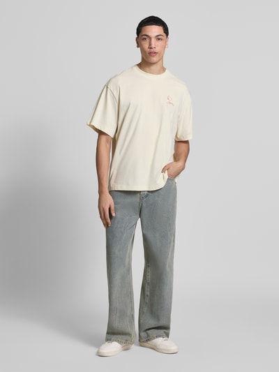 Männermodel trägt Regular Fit T-Shirt aus reiner Baumwolle Modell 'PEANUTS' von Only & Sons, cremefarben mit Peanuts® Print, Rundhalsausschnitt, kurzarm, Material Jersey; Ganzkörperansicht von vorne.