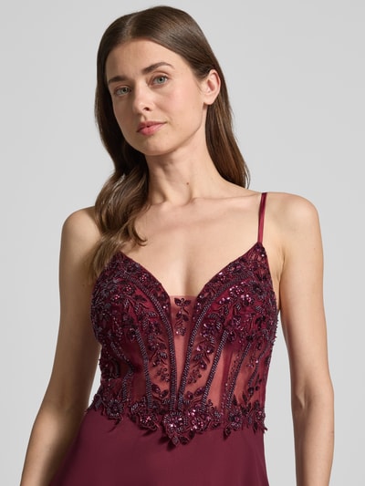 Frauenmodel trägt Abendkleid mit floralem Ziersteinbesatz von Laona in Bordeaux mit Spaghettiträgern, semitransparente Optik, Nahaufnahme Oberkörper.