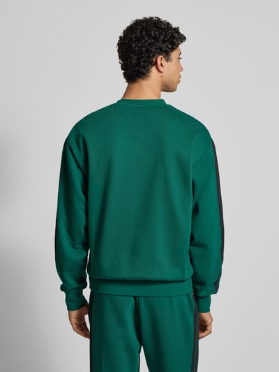 Männermodel trägt Sweatshirt mit Logo und Rundhalsausschnitt von adidas Sportswear im Baumwoll-Viskose-Mix, Relaxed-Fit, Ganzkörperansicht Rückansicht.