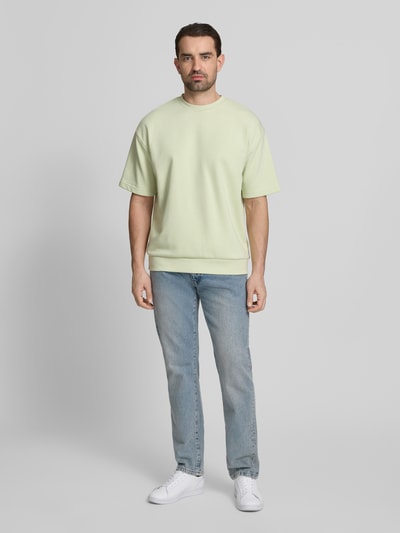 Mannenmodel draagt Oversized T-shirt met ronde hals van Lindbergh in lichtgeel, katoenmix, labeldetail, ruglengte maat M 70 cm. Ganzlichaamsaanzicht van voren.