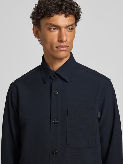 Männermodel trägt Modern Fit Overshirt mit Brusttasche Modell 'Kalan' von JOOP! Collection in Dunkelblau, Nahaufnahme Oberkörper.