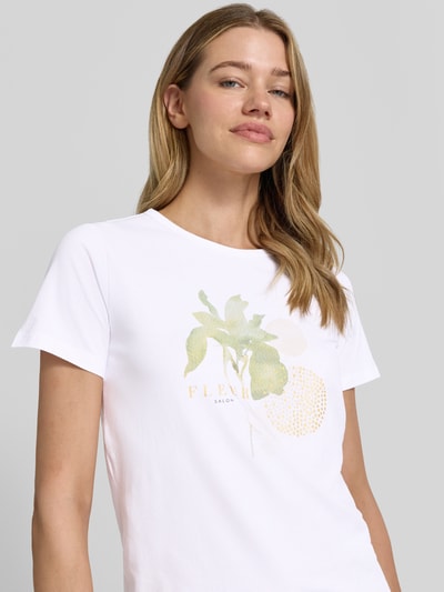 Frauenmodel trägt Damen T-Shirt mit Motiv-Print Modell 'RINA' von Soyaconcept aus Baumwoll-Elasthan-Mix, Regular-Fit, Rundhalsausschnitt, Weiß mit grün-gelbem Print, Rückenlänge bei Größe S 63 cm, Nahaufnahme Oberkörper.