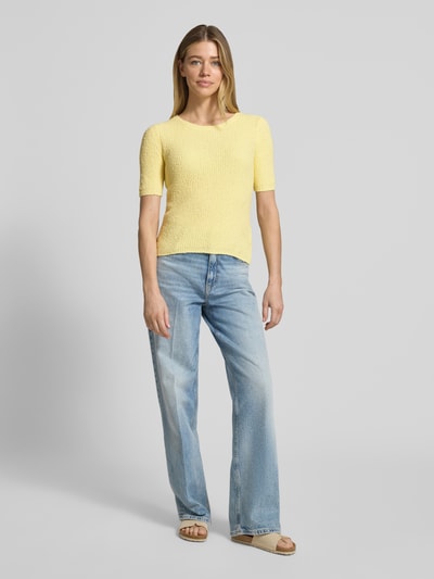 Frauenmodel trägt T-Shirt in Strick-Optik mit Rundhalsausschnitt von Rich & Royal, Damen T-Shirt aus Baumwoll-Mix, Straight Fit, meliertes Gelb, Rückenlänge bei Größe S 50 cm, Ärmellänge 28 cm, Ganzkörperansicht von vorne.