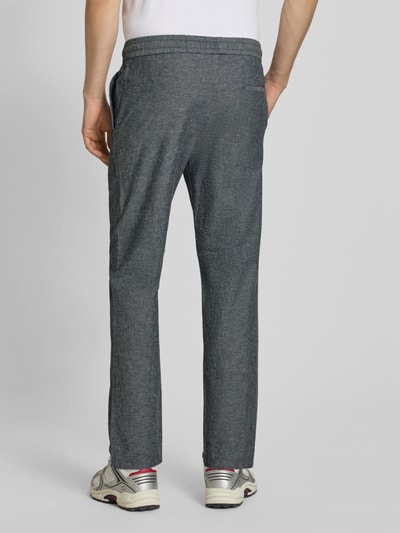 Männermodel trägt Tapered Leinenhose aus Baumwoll-Leinen-Mix Modell 'LINUS' von Only & Sons in Melange-Optik mit Gesäßtaschen, Ganzkörperansicht Rückansicht.