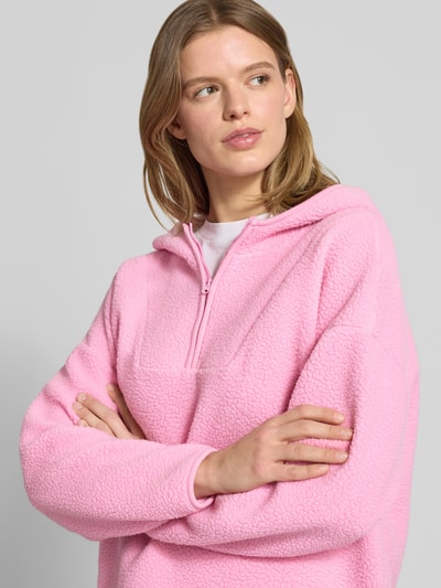 Frauenmodel trägt Hoodie aus Teddyfell Modell 'COZY' von Noisy May in Rosa, Regular Fit, mit Reißverschluss, Nahaufnahme Oberkörper.