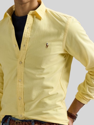 Männermodel trägt Slim Fit Freizeithemd aus reiner Baumwolle von Polo Ralph Lauren in Hellgelb, sichtbare Knöpfe, Nahaufnahme Oberkörper.