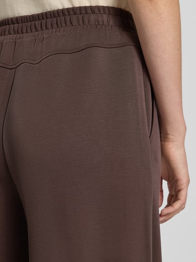 Vrouwenmodel draagt Wide Fit broek met viscose van comma, elastische materiaalmix, sierstrik, detailopname heup en band.