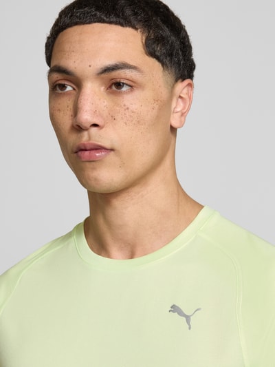 Mannenmodel draagt T-Shirt met Logo en Rundhalsausschnitt van PUMA PERFORMANCE in regular fit, pastelgroen, logo-opdruk, Nahaufnahme bovenlichaam.