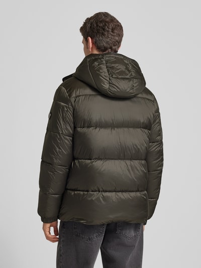 Męski model nosi Kurtka pikowana z kieszeniami zapinanymi na zamek błyskawiczny od JOOP! Collection, prosty krój, kaptur, ciemnozielony, długość tyłu 75 cm, szerokość ramion 49 cm, szerokość klatki 45 cm, długość rękawa 69 cm, tekstura lekko połyskująca, materiał gładki, całkowity widok z tyłu.