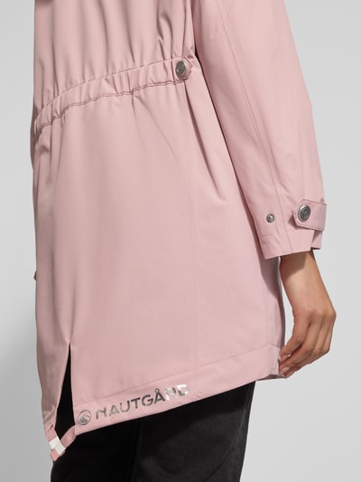 Frauenmodel trägt Jacke mit Ärmelriegeln von NAUTGÅRD in Rosa, glattes Material, sichtbare Knopfleiste, Detailaufnahme seitlich