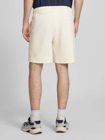 Männermodel trägt Shorts mit elastischem Bund und Label-Stitching von CHAMPION im Regular Fit, cremefarben, Baumwoll-Mix, Ganzkörperansicht Rückansicht.