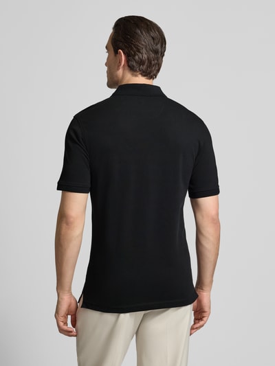 Männermodel trägt Regular Fit Poloshirt mit Logo-Detail Modell 'Pete' von BRAX, schwarzer Baumwoll-Mix, Kurzärmelig, Rückenlänge 74 cm, Ganzkörperansicht Rückansicht.