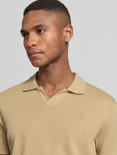 Męski model nosi Slim Fit Poloshirt aus Baumwoll-Mix von Polo Ralph Lauren, efekt: jednolity kolor, detal z logo, kołnierzyk polo, dekolt w serek, bez zapięcia, krótki rękaw, prążkowane zakończenia rękawów, wykończenie z rozcięciami po bokach, asymetryczny dół, wykończenie materiału: pika, mieszanka bawełny, zbliżenie na górną część ciała.