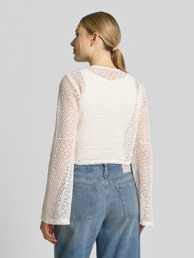 Frauenmodel trägt Strickjacke mit Knotendetail und Trompetenärmeln von Apricot, semitransparentes, cremefarbenes Grobstrickmuster, Ganzkörperansicht Rückansicht.