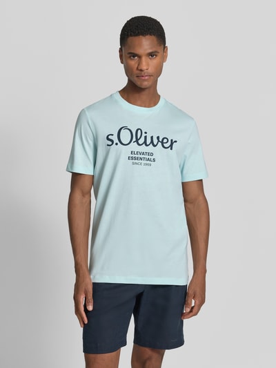 Męski model nosi Regular Fit T-Shirt aus reiner Baumwolle von s.Oliver RED LABEL, efekt: jednolity kolor, krój regular fit, nadruk z logo, okrągły dekolt, krótki rękaw, wykończenie materiału: dżersej, materiał: czysta bawełna, Ganzkörperansicht von vorne.