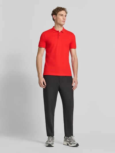 Mężczyzna nosi koszulkę polo Regular Fit z czystej bawełny model 'PIO 1' od BOSS Green, intensywnie czerwona, gładka, Ganzkörperansicht von vorne.