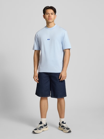 Männermodel trägt Regular Fit T-Shirt aus reiner Baumwolle Modell 'NIEROS' von Hugo Blue in Optik: Unifarben, Logo-Detail, Rundhals, Kurzarm, Herren T-Shirt, Ganzkörperansicht von vorne.