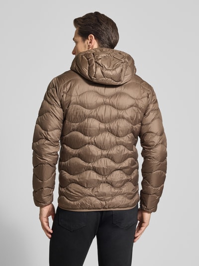 Męski model nosi Regular Fit Jacke mit Logo-Stitching Modell 'Helium' od Peak Performance, brązowy pikowany materiał, kaptur, zamek, elastyczne wykończenia, kieszenie na zamek, krój regular fit, perspektywa: całe ciało z tyłu