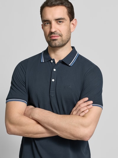 Męski model nosi Relaxed Fit Poloshirt mit Kontraststreifen od Lindbergh, bawełna, krój relaxed fit, granat, listwa guzikowa, stitching, długość tyłu w rozmiarze M: 67 cm, zbliżenie na górną część ciała