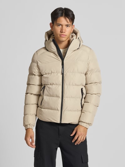 Männermodel trägt Superdry 'Steppjacke mit Label-Stitching und Kapuze' in beige mit ritssluiting, steekzakken, elastische mouwboorden, recht model; ruglengte maat M 67 cm, schouderbreedte 48 cm, borstwijdte 58 cm, mouwlengte 72 cm, Ganzkörperansicht van voren.