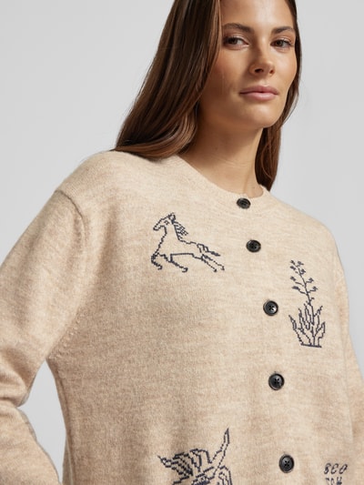 Frauenmodel trägt Strickjacke mit Stitchings und Rundhalsausschnitt von Scotch & Soda, Material-Mix mit Alpaka-Anteil, Knopfleiste, Nahaufnahme Oberkörper.