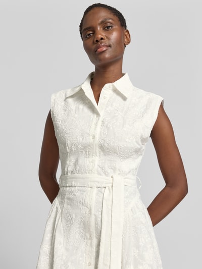 Frauenmodel trägt Maxikleid mit Bindegürtel Modell 'CATA' von Mango aus reiner Baumwolle in Weiß mit Umlegekragen und Knopfleiste, Nahaufnahme Oberkörper.