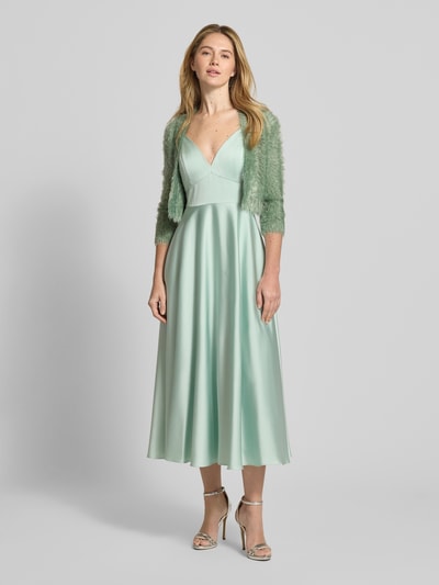 Frauenmodel trägt Bolero aus Kunstfell mit Viskose-Anteil von V.M., offener Vorderseite, 3/4-Arm, Material-Mix, sanftes Mintgrün, Ganzkörperansicht von vorne.