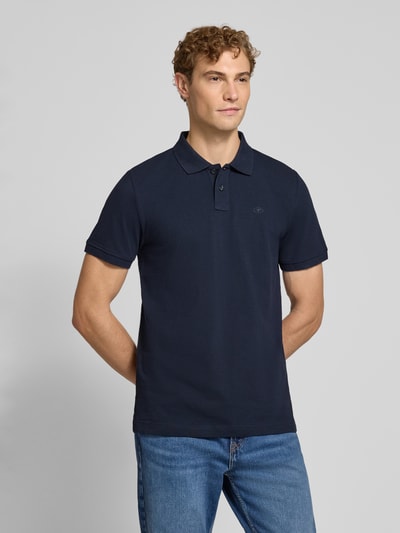 Męski model nosi Regular Fit Poloshirt aus Baumwoll-Mix von Tom Tailor, granatowa, gładka faktura, Ganzkörperansicht von vorne. Koszulka polo męska od Tom Tailor.