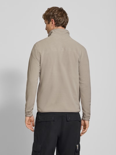 Männermodel trägt Fleecepullover mit Label-Stitching von The North Face in Beige, Regular Fit, Stehkragen, Rückenansicht, Ganzkörperansicht Rückansicht.