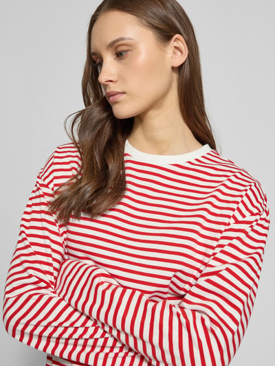 Modelka nosi Regular Fit Langarmshirt aus Baumwoll-Mix Modell 'SADIE' od Pieces, czerwono-białe paski, okrągły dekolt, długi rękaw, bawełniany materiał, optyka allover-muster, krój regular fit, zbliżenie na górną część ciała