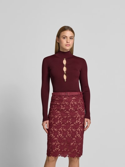 Frauenmodel trägt Slim Fit Longsleeve aus Viskose-Mix von Self-Portrait in Dunkelrot mit Cut-Outs und Zierbesatz, Ganzkörperansicht von vorne.